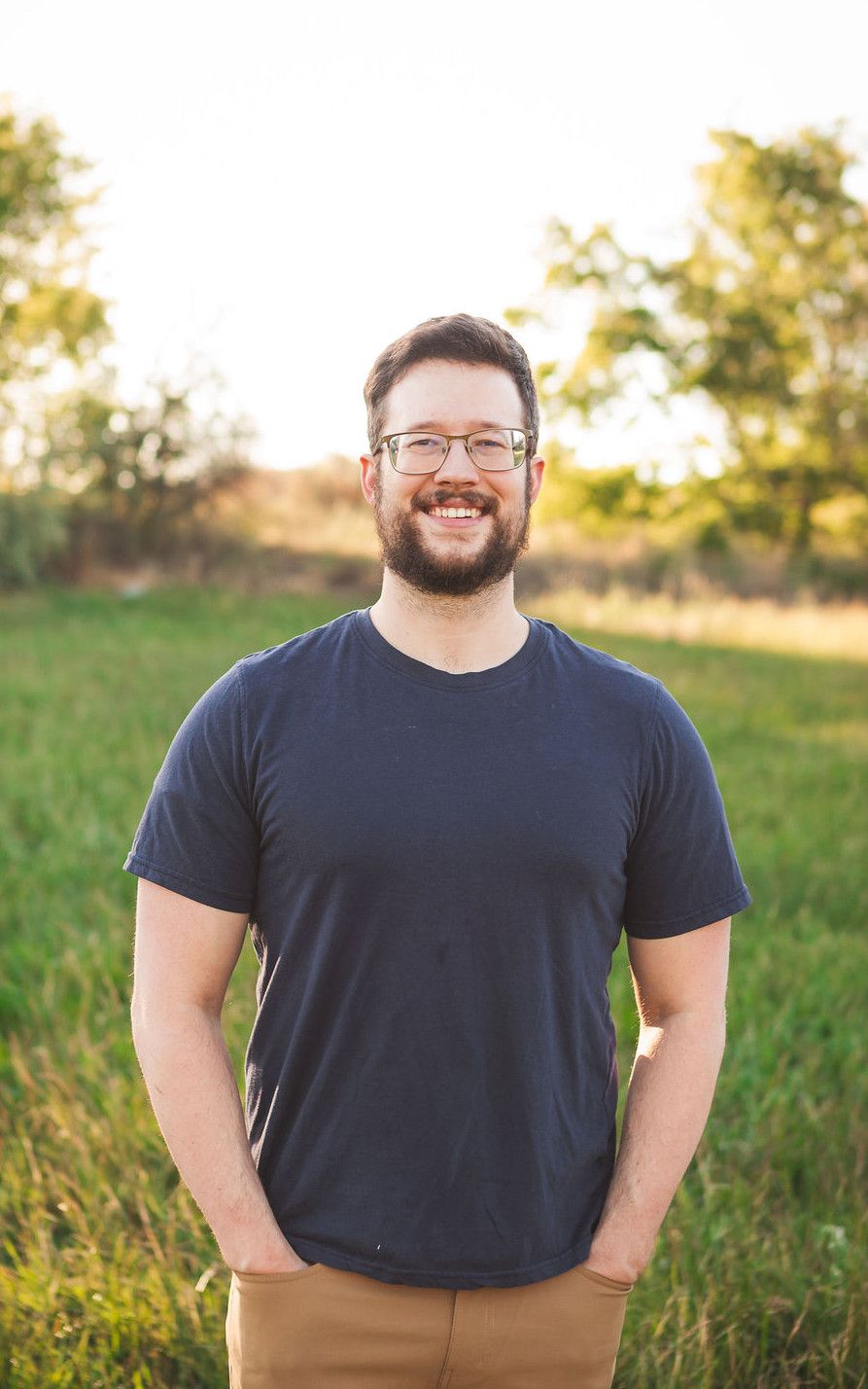 Ethan Fausett, standing in a field at golden hour, hands in his pockets.